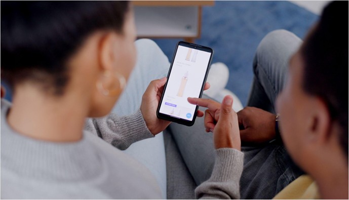 Two people sitting together looking at a product page on a smartphone, viewed from behind