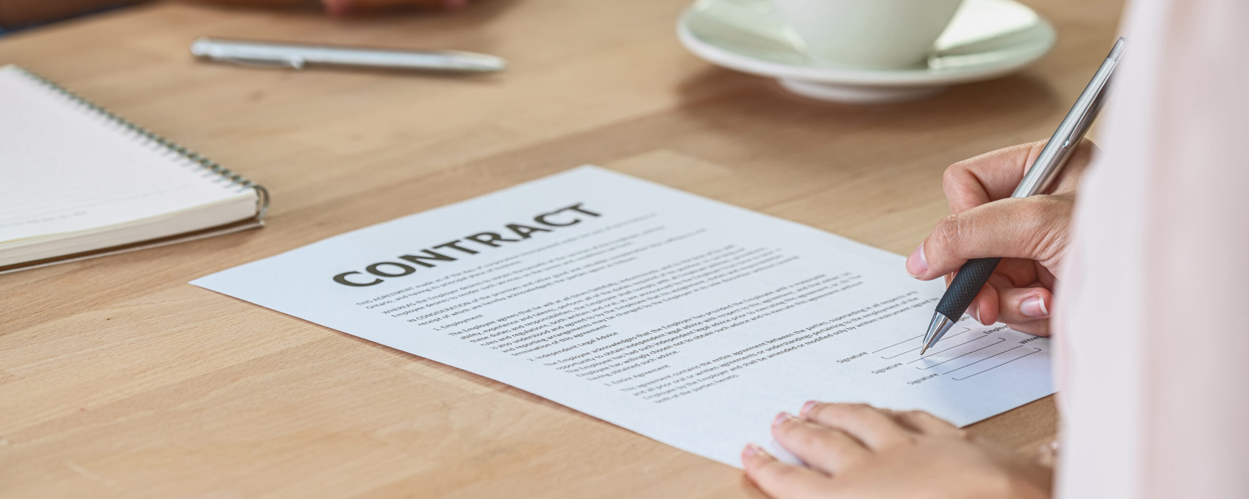 signing a contract on a wooden desk